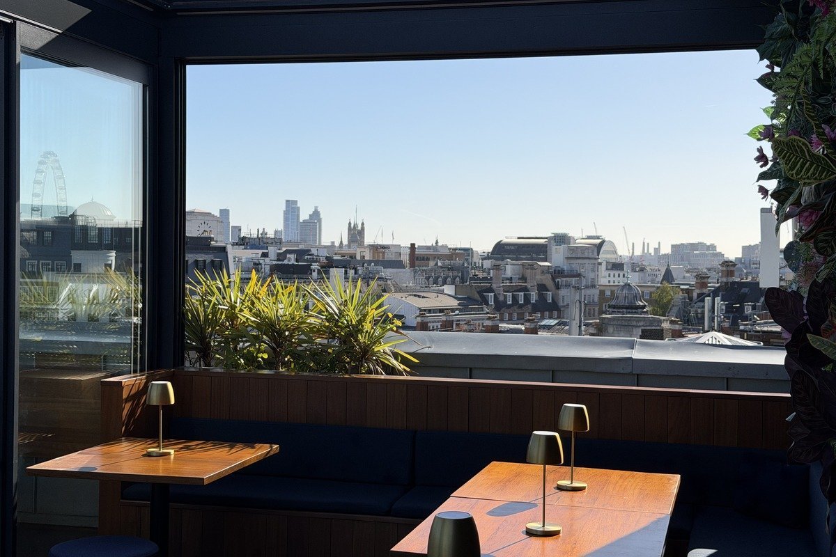 Tables en bois et lampes dorées dans un bar en hauteur avec vue panoramique