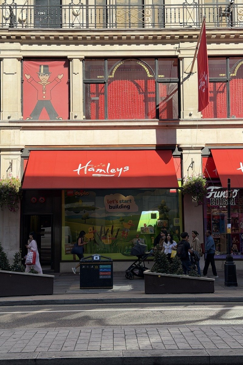 Façade rouge d'un grand magasin de jouets avec passants sur trottoir