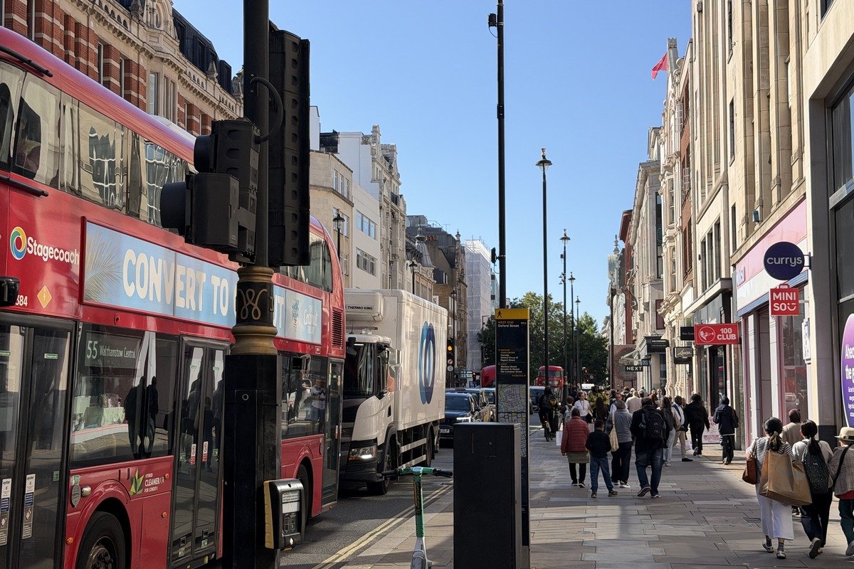 Rue animée avec bus rouges à impériale et piétons sous ciel bleu