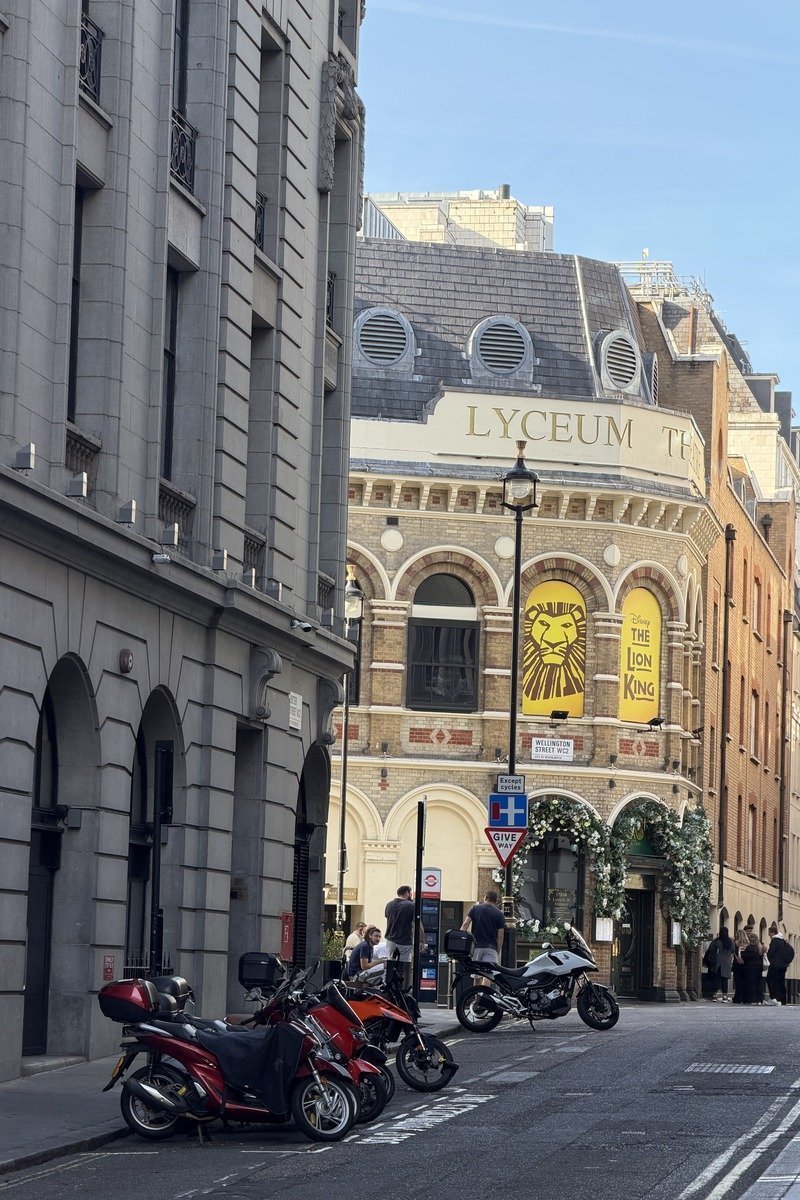 Façade d'un théâtre victorien avec affiche du Roi Lion et motos garées