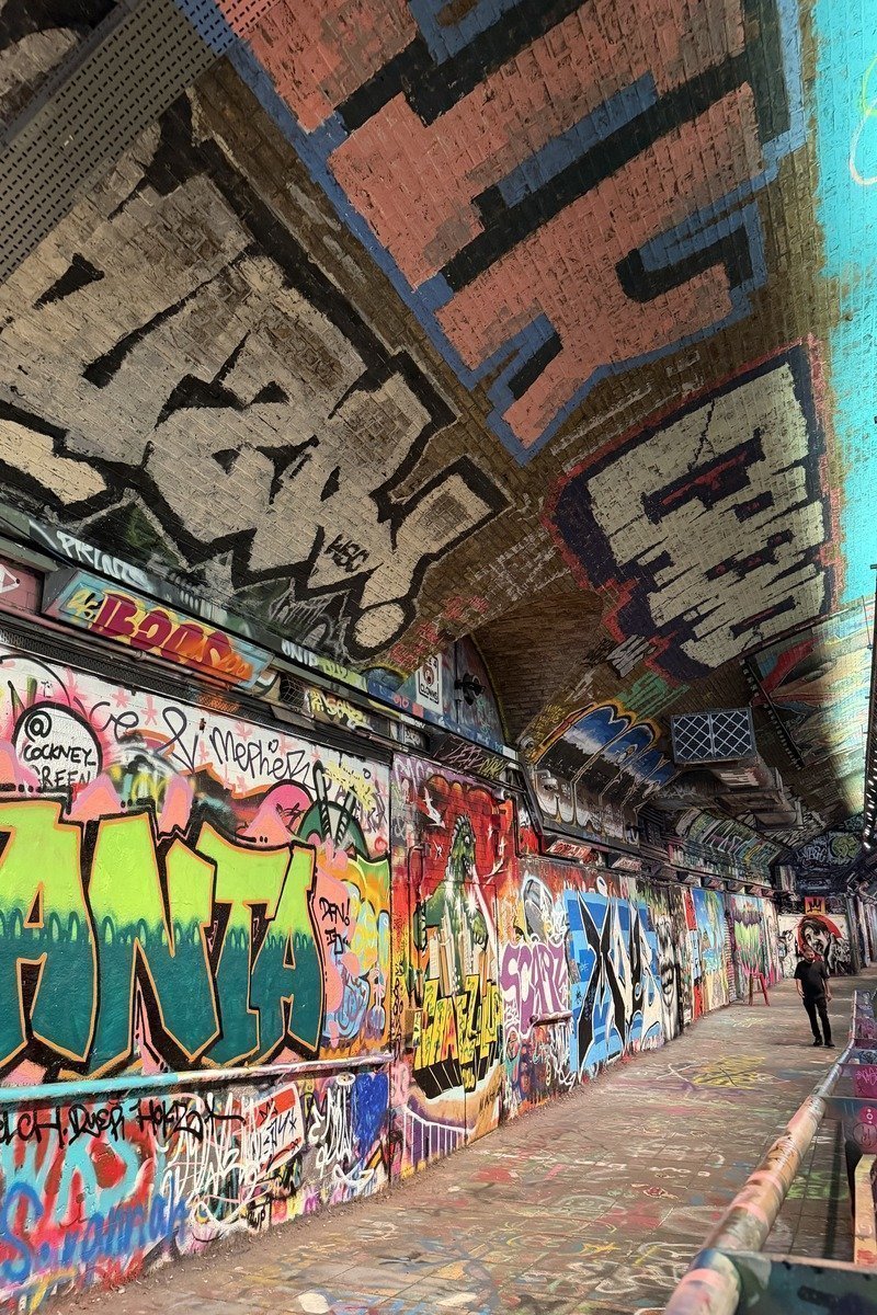 Tunnel couvert entièrement recouvert de graffitis colorés avec un passant
