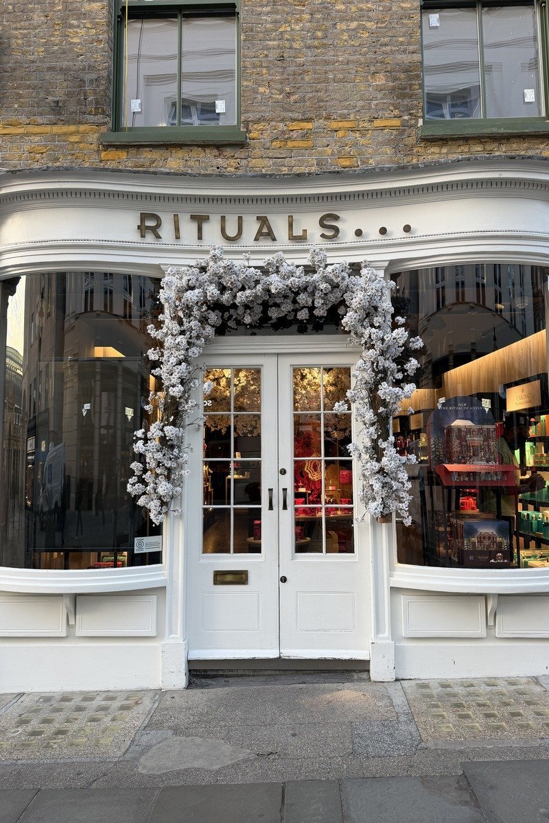 Façade blanche d'une boutique décorée d'une arche de fleurs blanches