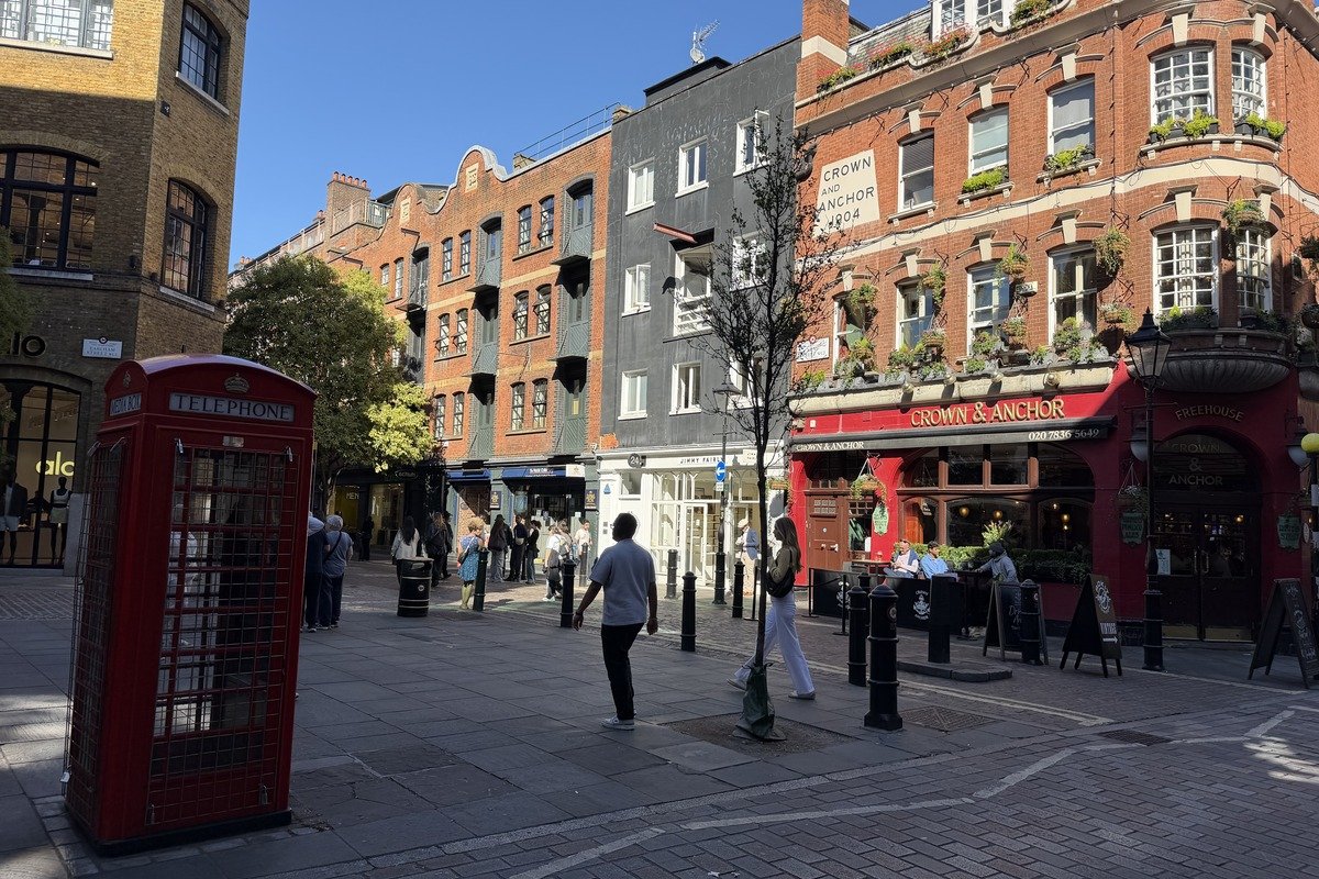 Cabine téléphonique rouge sur une place piétonne animée avec pub victorien