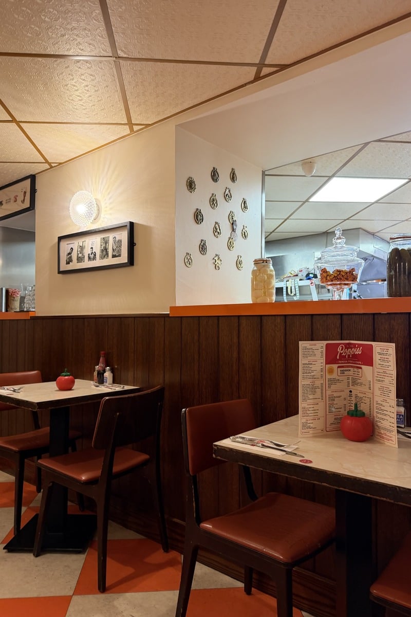 Salle de restaurant rétro avec tables, chaises en vinyle rouge et sol damier orange