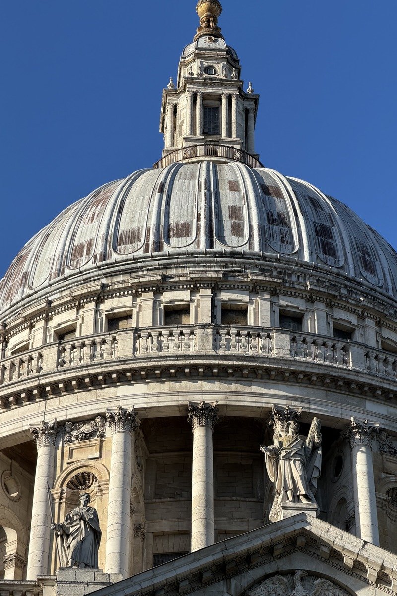 Dôme baroque en pierre avec statues et lanternon doré sous ciel bleu