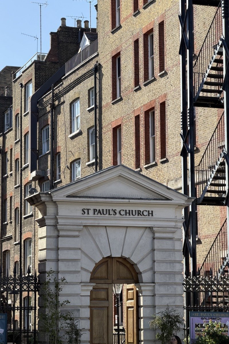 Portique blanc d'une église encadré de bâtiments en briques