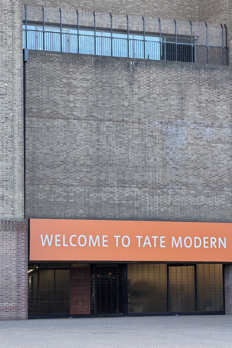 Entrée d'un musée en briques avec enseigne orange et texte blanc