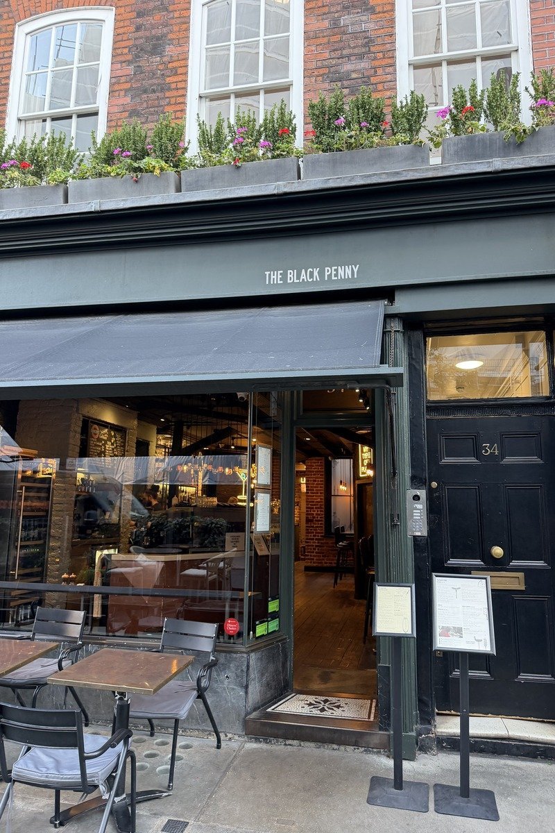 Devanture d'un café avec auvent vert sombre et tables extérieures