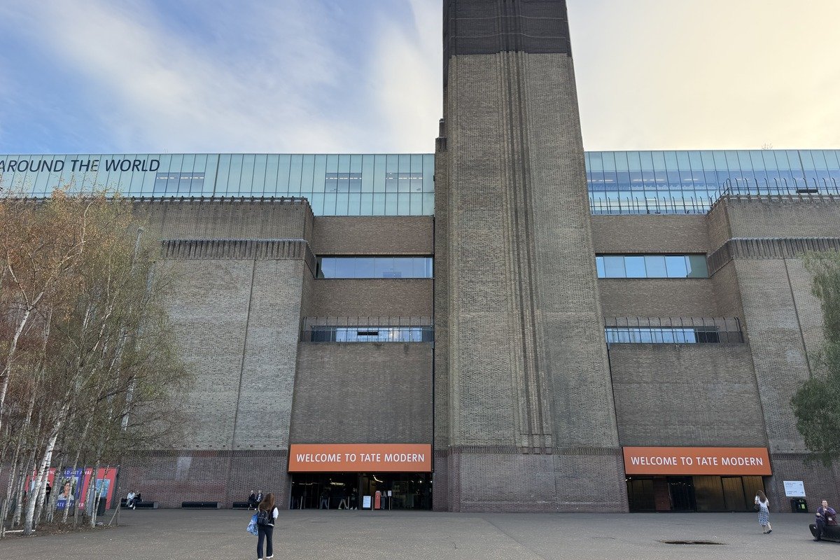 Façade en brique d'un grand musée avec cheminée centrale et enseignes orange