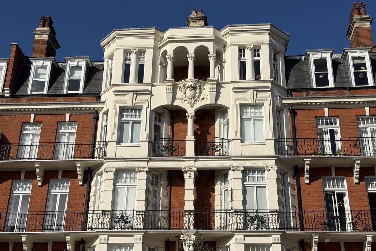 Façade victorienne en brique rouge et pierre blanche avec balcons en fer forgé