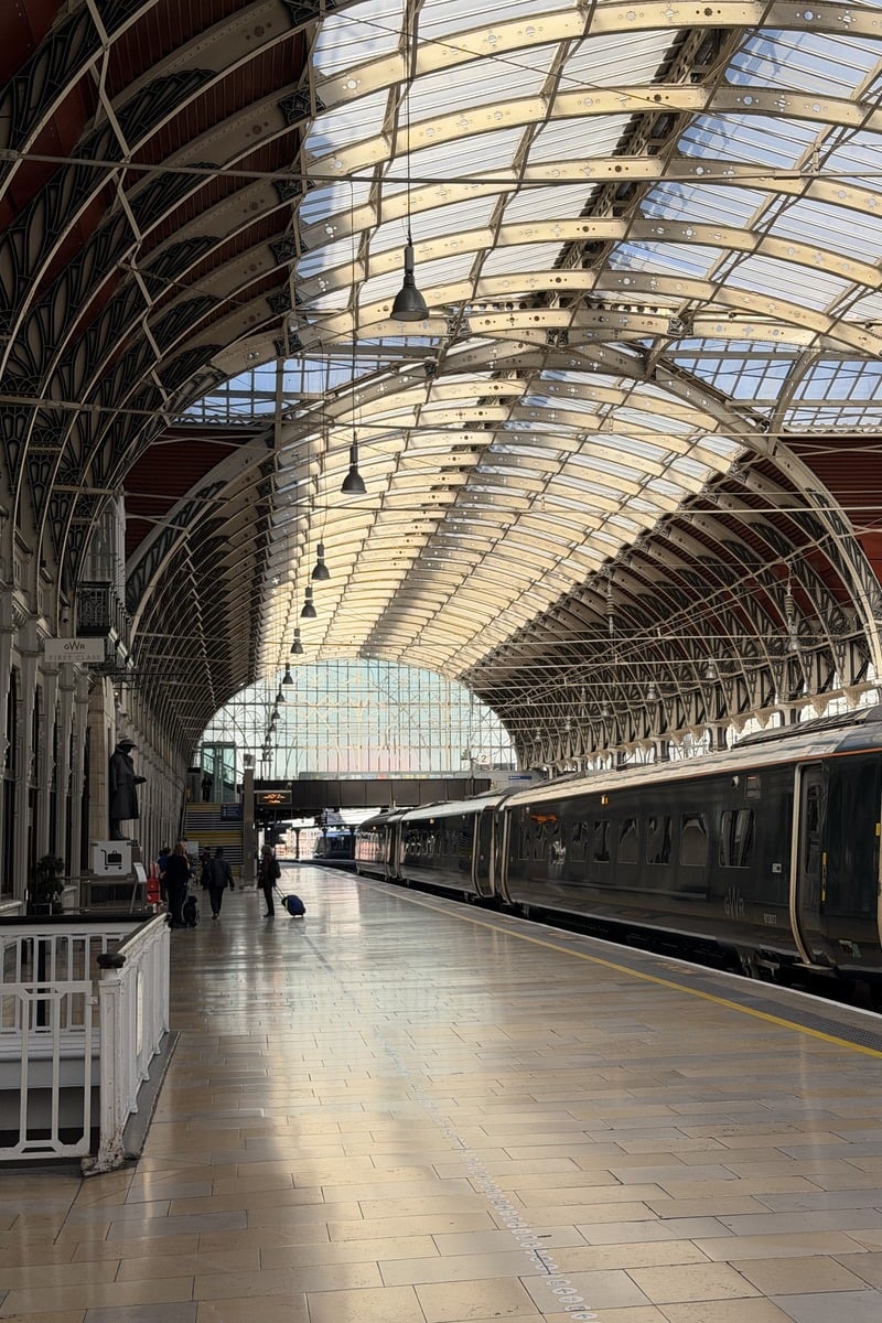 Quai de gare victorienne avec train sombre sous grande verrière métallique