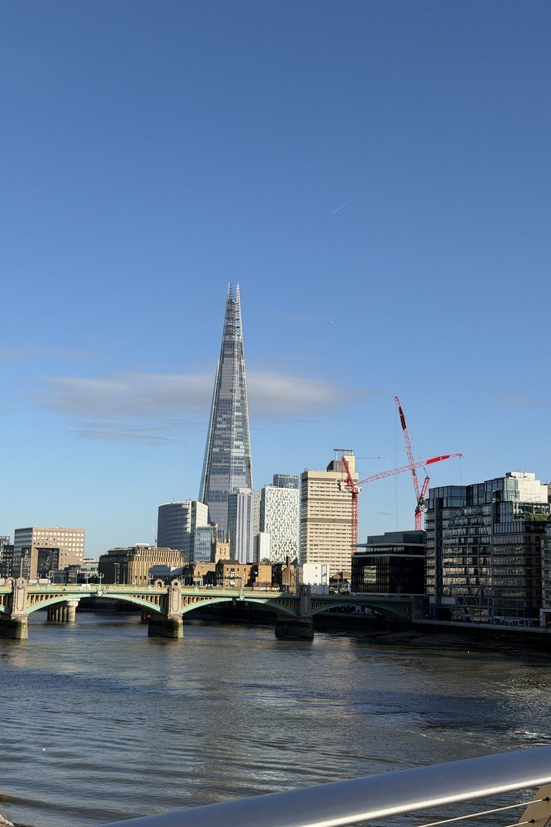 Gratte-ciel en verre dominant un pont et une rivière sous ciel bleu