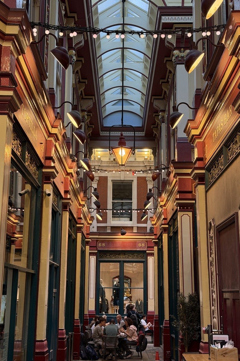 Galerie couverte victorienne avec verrière, lampes suspendues et devantures colorées