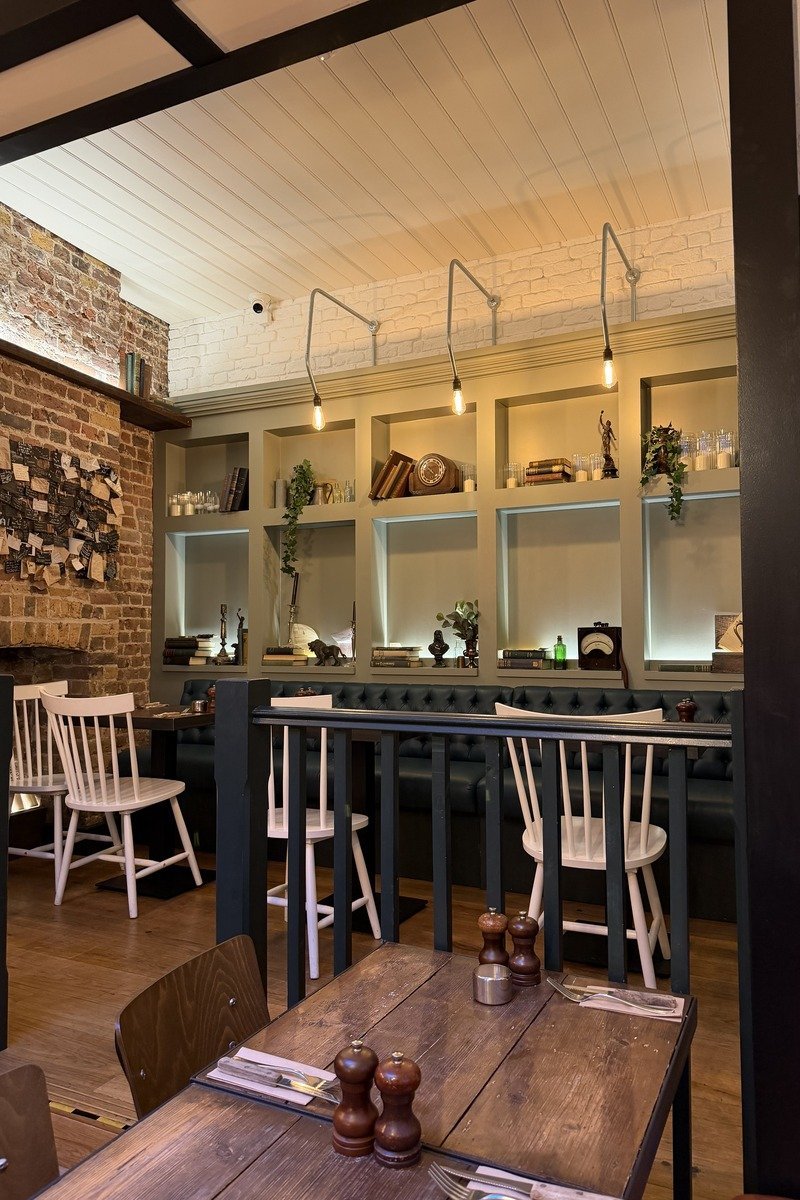 Intérieur de restaurant avec chaises blanches, banquettes et étagères décorées