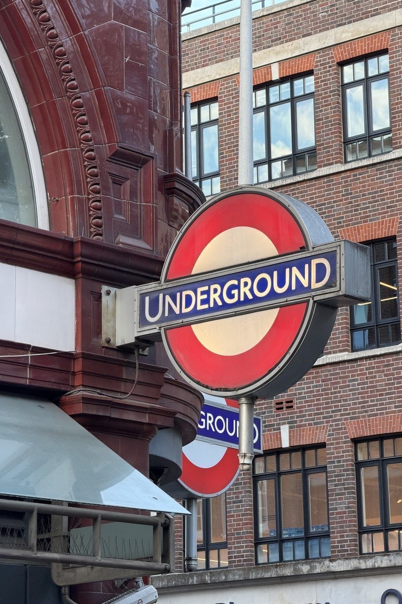 Panneau rond rouge et bleu du métro devant façade en brique