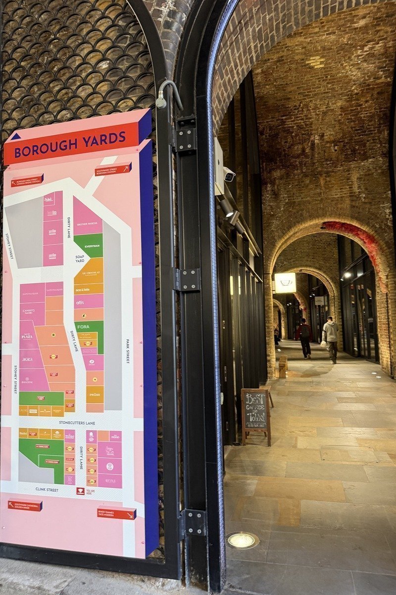 Panneau de plan coloré à l'entrée d'une galerie marchande sous arcades en briques