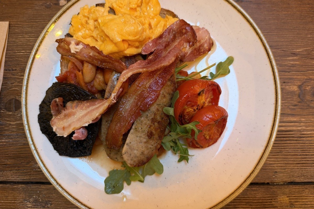 Assiette de petit-déjeuner complet avec saucisses bacon œufs brouillés et tomates grillées