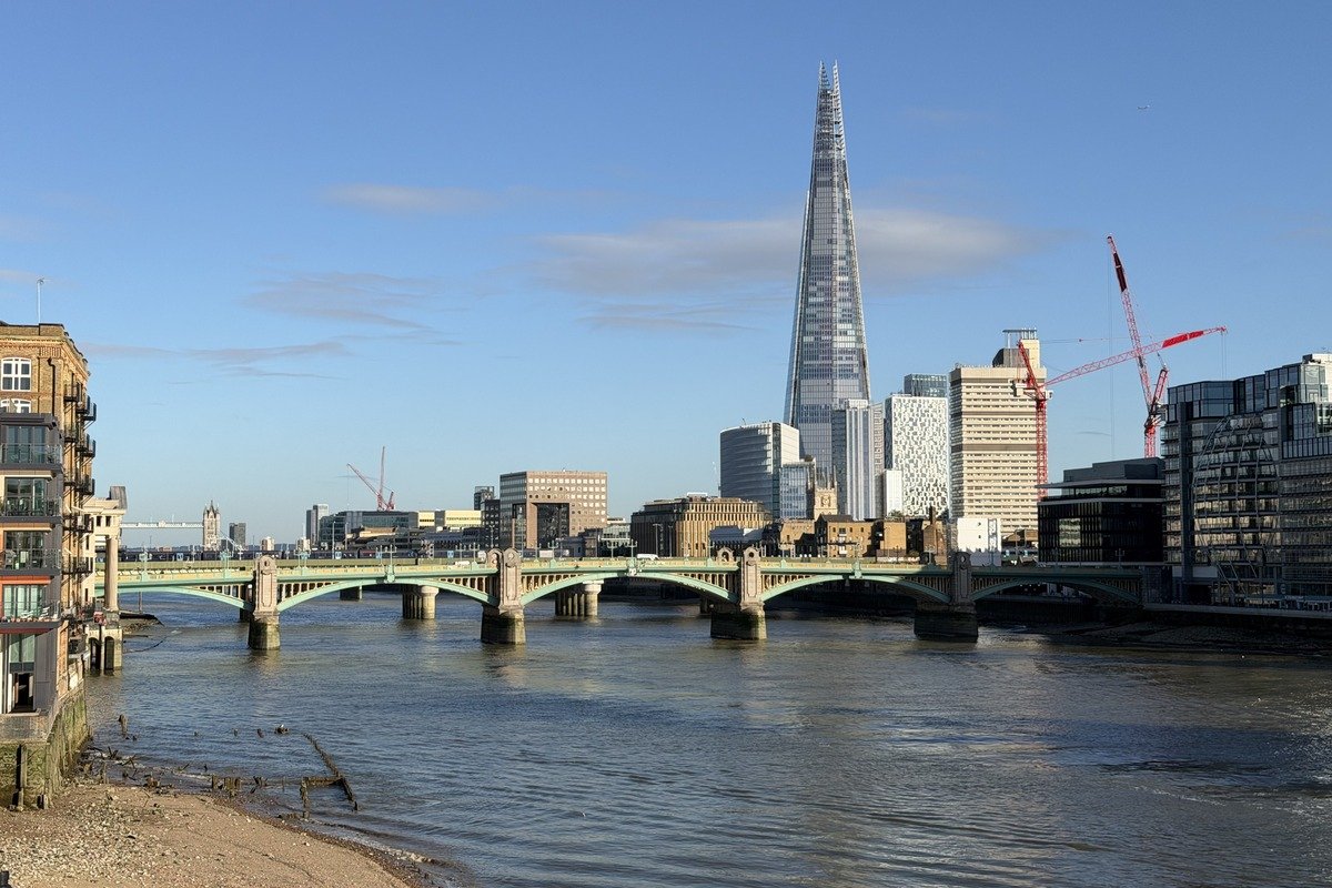 Pont sur une rivière avec gratte-ciel en pointe dominant la skyline