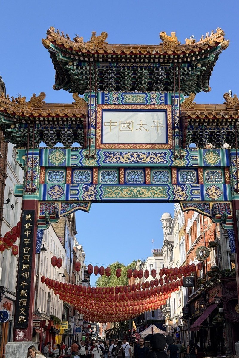 Portail traditionnel chinois orné surplombant une rue animée avec lanternes rouges