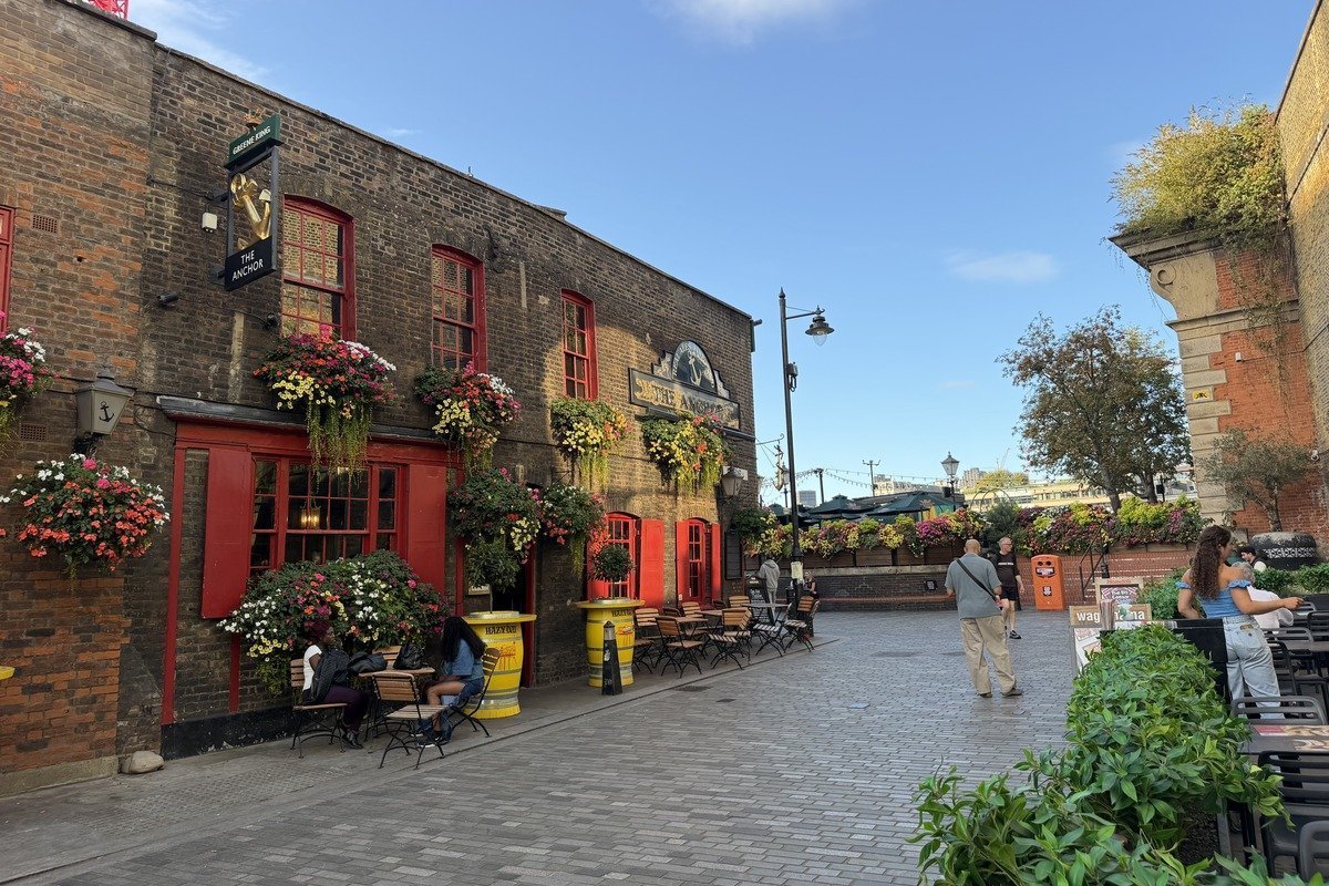 Pub en briques rouges orné de jardinières fleuries colorées et terrasse pavée