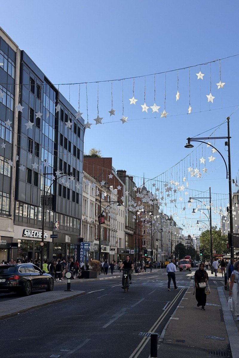 Grande rue commerçante animée avec guirlandes d'étoiles suspendues et ciel bleu