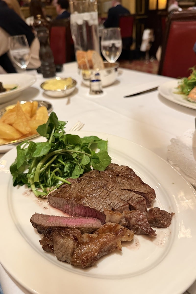 Pièce de bœuf tranchée saignante avec cresson et frites sur assiette blanche
