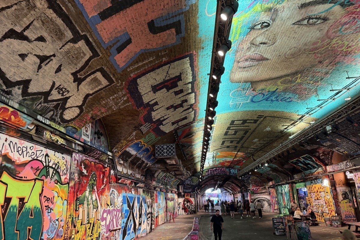 Tunnel couvert de graffitis colorés avec un portrait mural au plafond